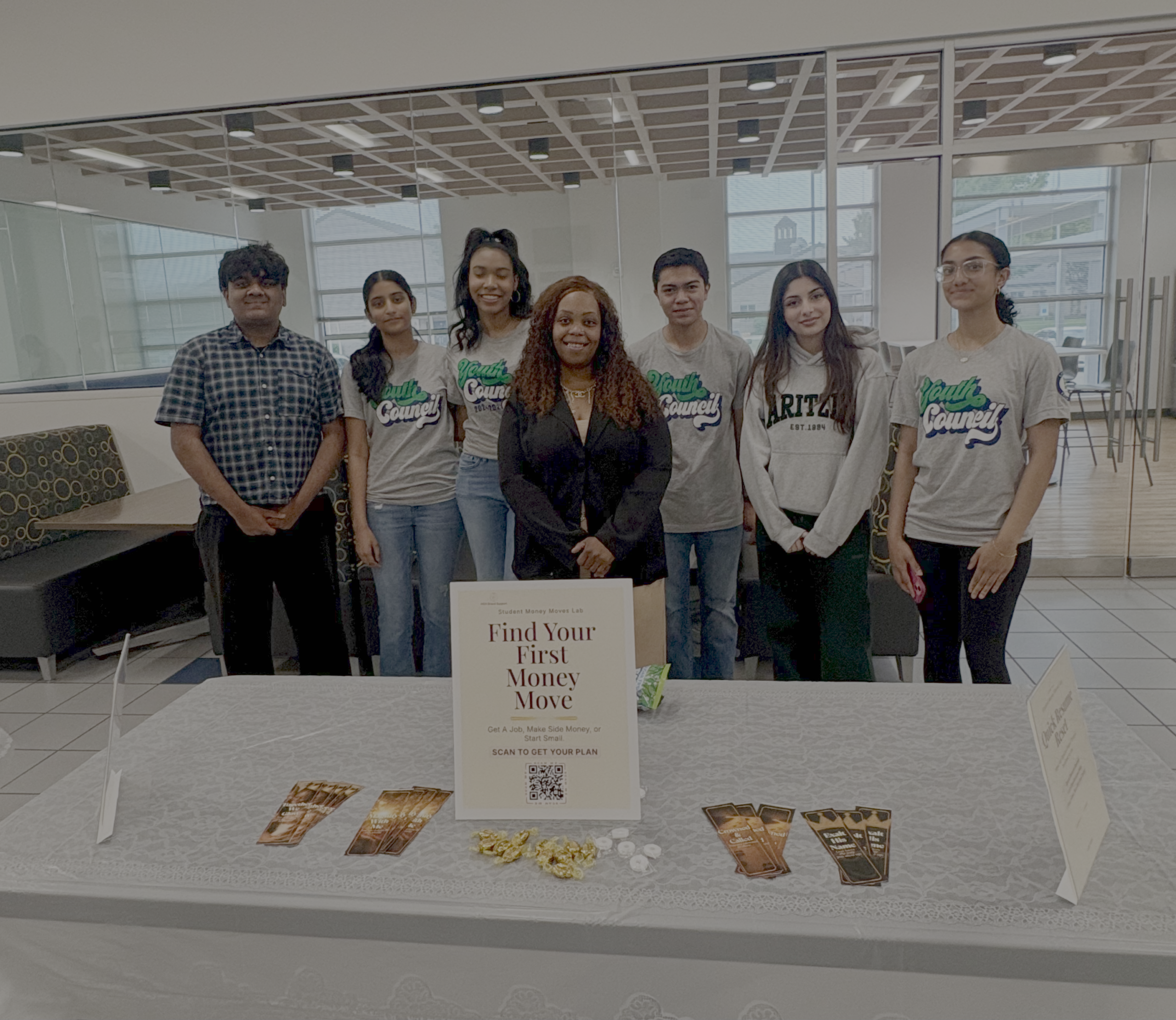 Sarah with job fair participants behind the prepared Student Money Moves Lab outreach table at the LE Job Fair.